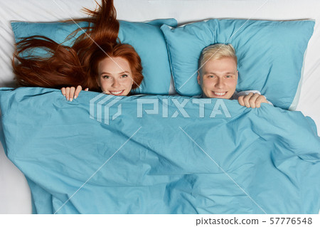 positive blonde man and ginger woman lying on the bed 57776548
