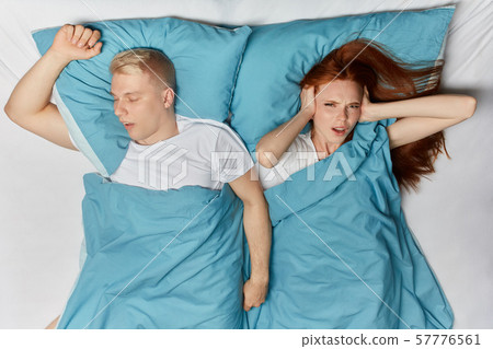 blonde man snoring and angry ginger woman cannot sleep. blonde man snoring and angry ginger woman cannot sleep. 57776561