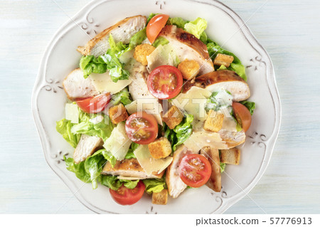 Caesar salad close-up. Slices of chicken breast, green lettuce, Parmesan cheese, croutons, and Caesar salad close-up. Slices of chicken breast, green lettuce, Parmesan cheese, croutons, and 57776913