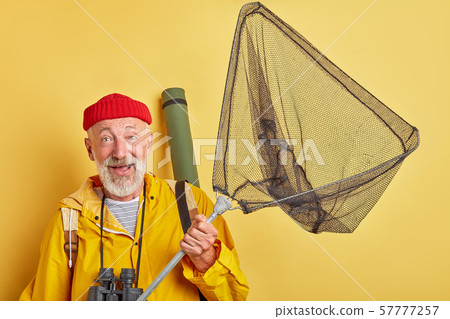 excited happy old man in red cap and yellow coat holding fishnet excited happy old man in red cap and yellow coat holding fishnet 57777257
