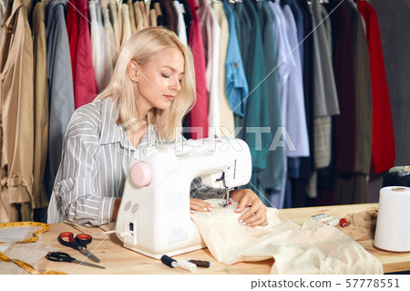 young eamstress using her sewing mahcine at the tailoring shop 57778551