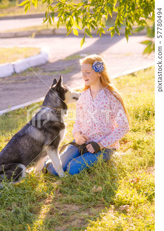 Cute teen girl with red long hair walks with her husky breed dog in the autumn park. Children and dogs. Autumn mood Cute teen girl with red long hair walks with her husky breed dog in the autumn park. Children and dogs. Autumn mood 57780494