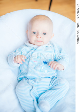Adorable baby boy in white sunny bedroom. Newborn child relaxing in bed. Nursery for young children. Textile and bedding for kids. Family morning at home Adorable baby boy in white sunny bedroom. Newborn child relaxing in bed. Nursery for young children. Textile and bedding for kids. Family morning at home 57780726