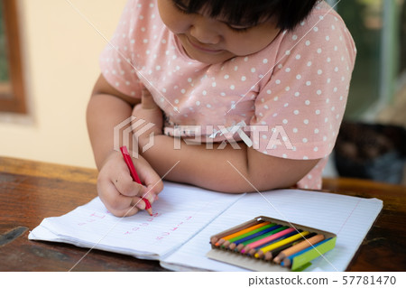 Close up of girl hand with pencil writing english words by hand on  white notepad paper at white background 57781470