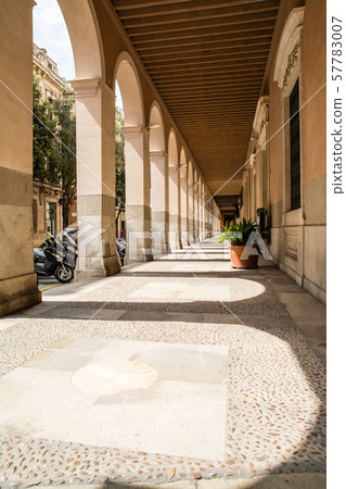 Corridor of buildings with pastel columns under strong sunlight (Majorca cityscape) 57783007