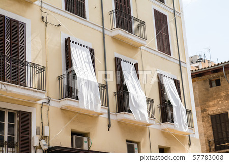 馬略卡島城市景觀輕質奶油建築，帶有棕色遮陽門窗和遮陽篷 57783008