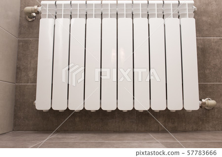 White radiator in the bathroom close-up. Heating. Tiled gray wall. 57783666