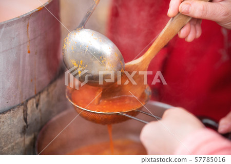 Making Tomato Sauce on the Stove. A close up of the hand mill griinding up the fresh field tomatoes Making Tomato Sauce on the Stove. A close up of the hand mill griinding up the fresh field tomatoes 57785016