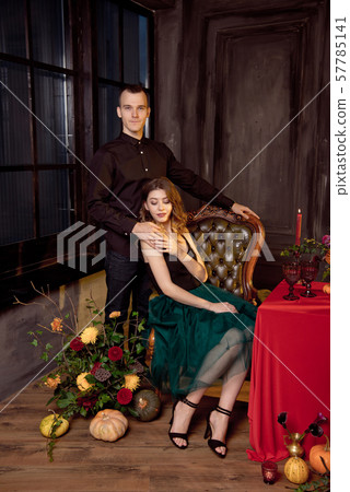 Happy Halloween. Attractive young woman and man preparing for Halloween by setting the table for a 57785141
