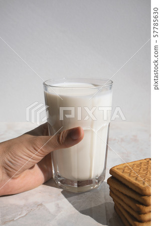 Hand holding full glass of milk on a table and 57785630