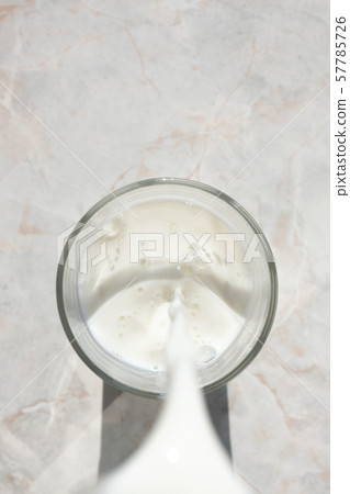 Flowing milk. Close-up of milk stream pouring into 57785726