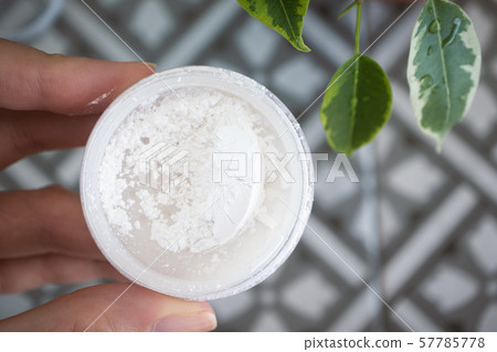 Female hand holding white mineral powder in a Female hand holding white mineral powder in a 57785778