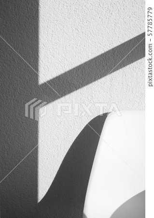 White chair back in front of white textured wall White chair back in front of white textured wall 57785779
