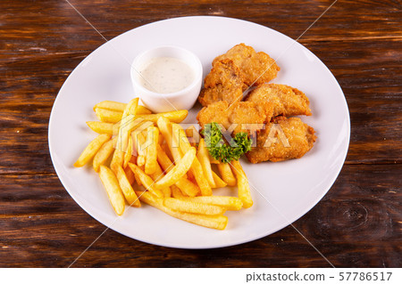 Chicken nuggets, are served with French fries and creamy sauce Chicken nuggets, are served with French fries and creamy sauce 57786517