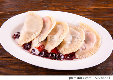 Cherry vareniki, are served with berries of cherry and sour cream 57786641