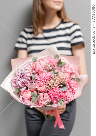 Beautiful bouquet of mixed flowers in womans hands. the work of the florist at a flower shop Beautiful bouquet of mixed flowers in womans hands. the work of the florist at a flower shop 57789390