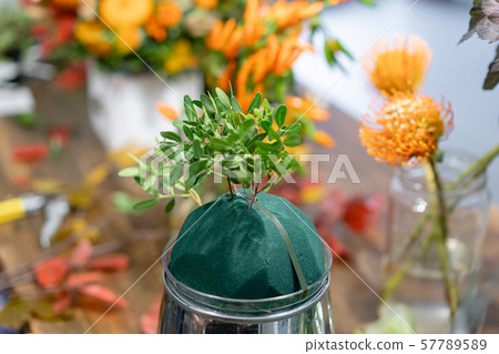 Process of creating Autumn bouquet of mixed flowers on wooden table. The work of the florist at a Process of creating Autumn bouquet of mixed flowers on wooden table. The work of the florist at a 57789589
