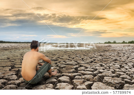 Water crisis, man sit on cracked earth near drying 57789974