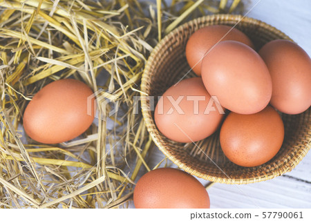 Fresh egg on basket and straw with wooden table Fresh egg on basket and straw with wooden table 57790061