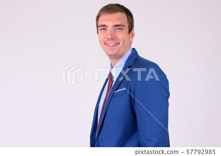 Profile view of happy businessman in suit smiling and looking at camera Profile view of happy businessman in suit smiling and looking at camera 57792985