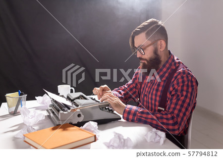 People and technology concept - Writer sits at a table surrounded by scraps of paper People and technology concept - Writer sits at a table surrounded by scraps of paper 57794812
