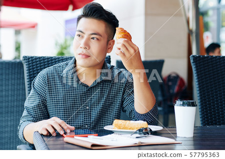 Vietnamese man enjoying coffee and pastries 57795363