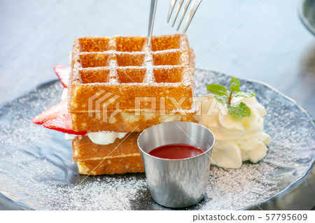 Waffle Strawerry fresh cream in the black plate on wooden table. 57795609