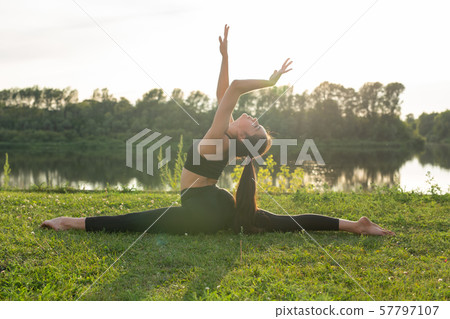 Young woman enjoying relaxing yoga outdoors in the park. 57797107