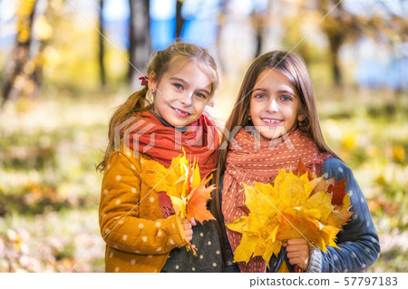Two cute smiling 8 years old girls posing together in a park on a sunny autumn day. Two cute smiling 8 years old girls posing together in a park on a sunny autumn day. 57797183