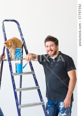 Renovation, redecoration and family concept - Young man stroking a cat during renovation in Renovation, redecoration and family concept - Young man stroking a cat during renovation in 57797392