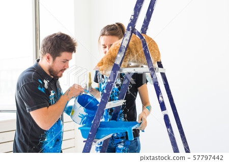 People, redecoration and renovation concept - portrait of couple with cat pour paint People, redecoration and renovation concept - portrait of couple with cat pour paint 57797442