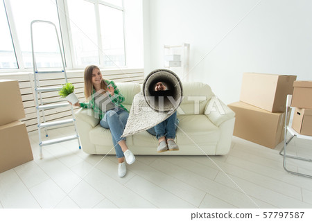 Funny young couple charming girl and handsome man holding a box with things and a pot with a plant Funny young couple charming girl and handsome man holding a box with things and a pot with a plant 57797587