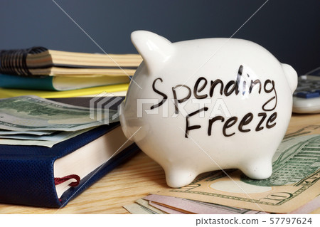 Spending freeze written on a side of piggy bank. Spending freeze written on a side of piggy bank. 57797624