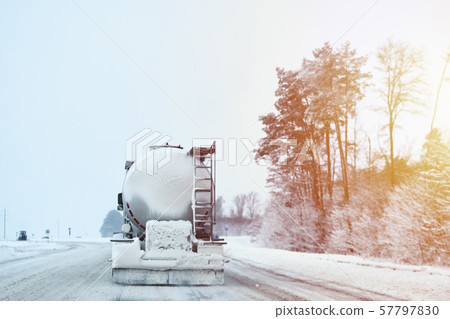 Truck with cargo tank on a slippery snow winter road outside the city, back view Truck with cargo tank on a slippery snow winter road outside the city, back view 57797830