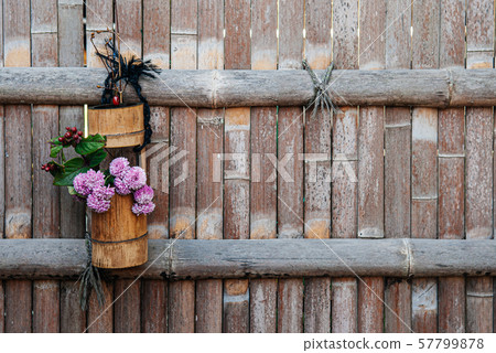 Flower in bamboo vase hanging on bamboo fence Flower in bamboo vase hanging on bamboo fence 57799878