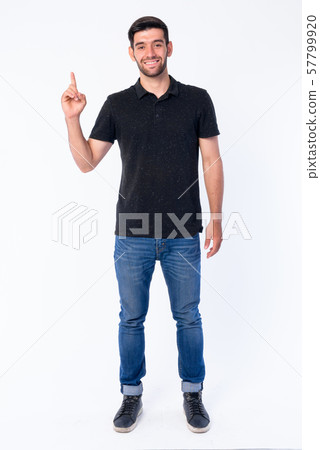 Full body shot of happy young bearded Persian man pointing up 57799920