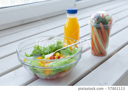 Bowl of green salad, raw vegetables and bottle of orange juice. Weight loss, diet and right 57801113