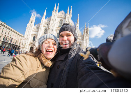 Winter travel and vacations concept - Happy tourists taking a self portrait with funny pigeons in 57801280