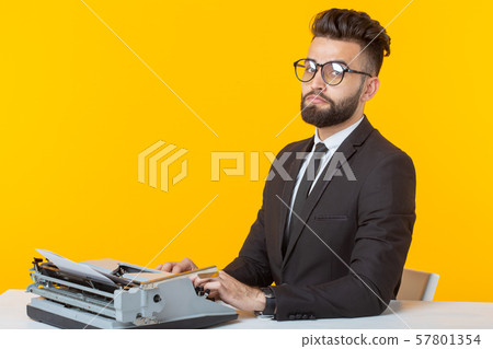 Arab businessman or manager in formal suit typing text on a typewriter on a yellow background 57801354