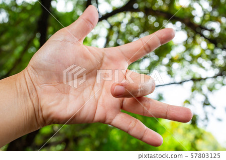 Trigger Finger lock on middle finger of woman's left hand, Suffering from pain, Bokeh green garden background, Health care concept Trigger Finger lock on middle finger of woman's left hand, Suffering from pain, Bokeh green garden background, Health care concept 57803125