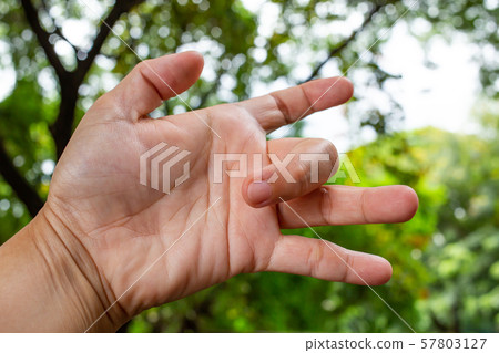 Trigger Finger lock on middle finger of woman's left hand, Suffering from pain, Bokeh green garden background, Health care concept Trigger Finger lock on middle finger of woman's left hand, Suffering from pain, Bokeh green garden background, Health care concept 57803127