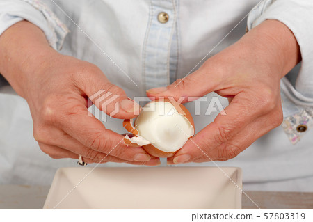 close up of hands of woman shells hard-boiled egg 57803319