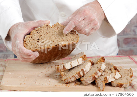 Baker hands with fresh bread on wood table 57804500