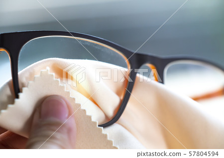 Woman's hand cleaning black eyeglasses by microfibre cleaning cloths, Close up & Macro shot, Selective focus, Optical concept 57804594