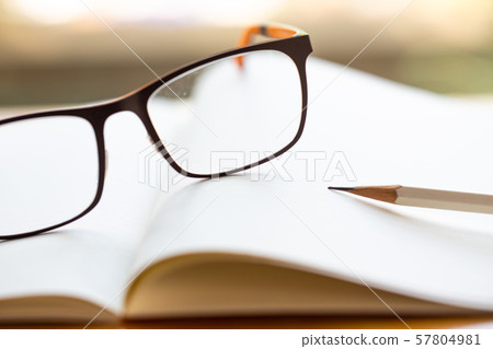 Black eyeglasses, white pencil with white notebook on wooden table, Close up & Macro shot, Selective focus, Stationery concept Black eyeglasses, white pencil with white notebook on wooden table, Close up & Macro shot, Selective focus, Stationery concept 57804981