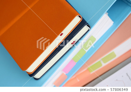 Stack of books with paper foder lie in office against Stack of books with paper foder lie in office against 57806349