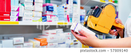 pharmacist using yellow labeling gun for sticking price label of medicine in pharmacy  57809140