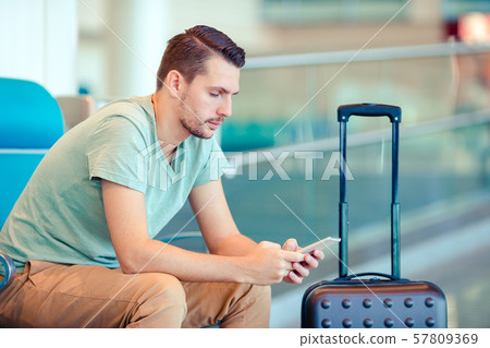 Young man in an airport lounge waiting for flight aircraft. 57809369