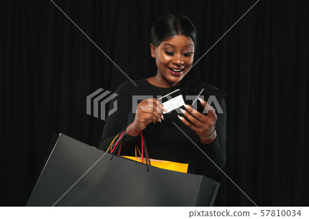 Young woman in dress shopping on black background Young woman in dress shopping on black background 57810034