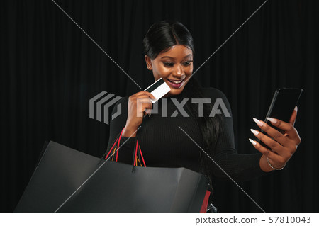 Young woman in dress shopping on black background 57810043